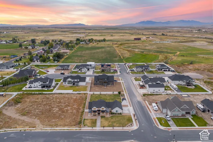 Aerial perspective of a suburban neighborhood featuring paved cul-de-sac streets, residential lots with concrete driveways, and expansive mountain scenery