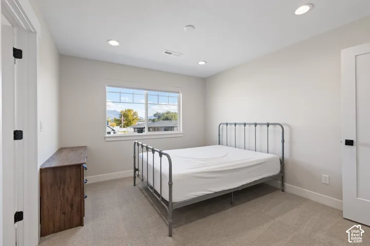 Neutral-toned bedroom featuring recessed lighting, wall-to-wall carpeting, and a double-hung window with a multi-pane upper sash