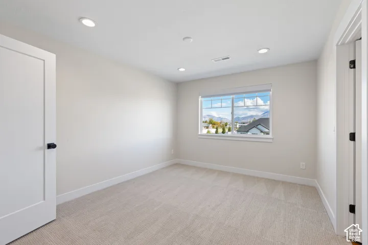 Neutral-toned bedroom featuring recessed lighting, wall-to-wall carpeting, shaker-style doors with matte black hardware, and a window with mountain scenery