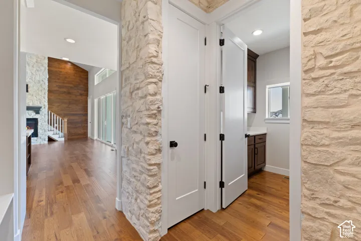 Natural stone accent wall, hardwood flooring, solid-core shaker style interior doors, recessed ceiling lighting, and dark-finish built-in cabinetry