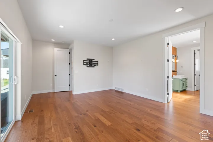 Primary bedroom featuring hardwood flooring, recessed lighting, and a sliding glass door to covered patio