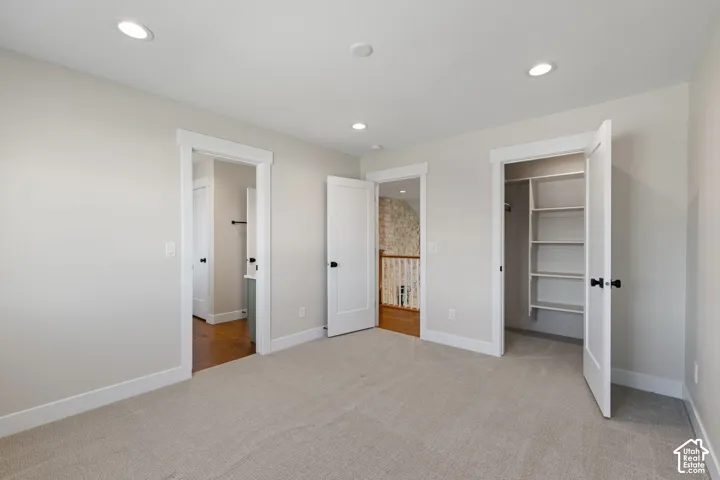 Neutral carpeting, recessed lighting, and solid-core interior doors with matte black hardware, featuring a walk-in closet with integrated shelving
