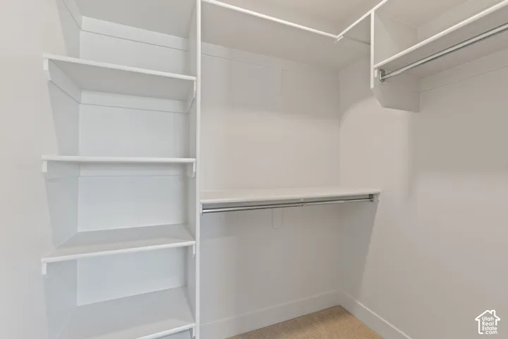 Walk-in custom closet storage system featuring white shelving and dual-level metal hanging rods