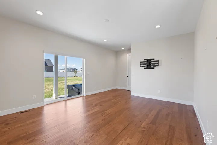 Primary bedroom featuring hardwood flooring, recessed lighting, and a sliding glass door to covered patio