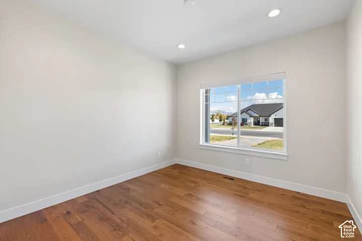Main floor bedroom featuring hardwood flooring, neutral walls, recessed lighting, and a window with a mountain backdrop