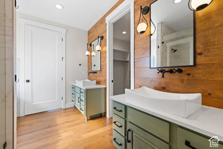 Bathroom featuring dual vanities with white vessel sinks, quartz countertops, horizontal wood-plank wall treatments, and wall-mounted matte black faucets