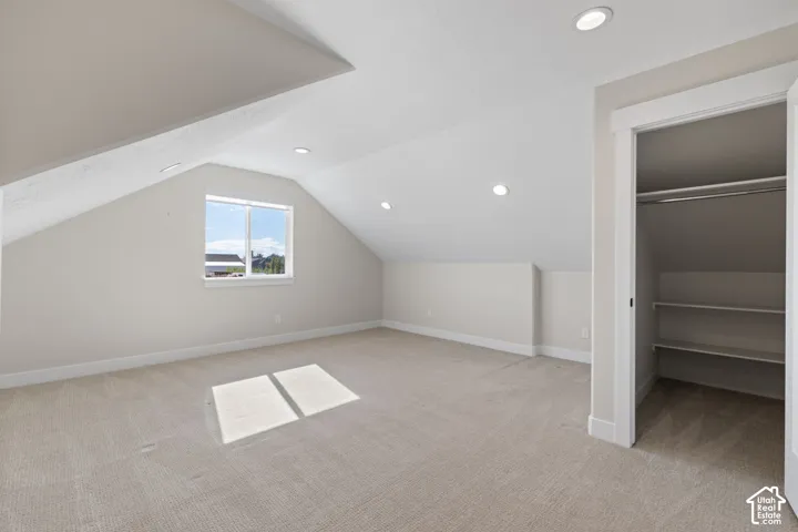 Sloped ceilings featuring recessed lighting, carpeted flooring, and a walk-in closet with built-in shelving