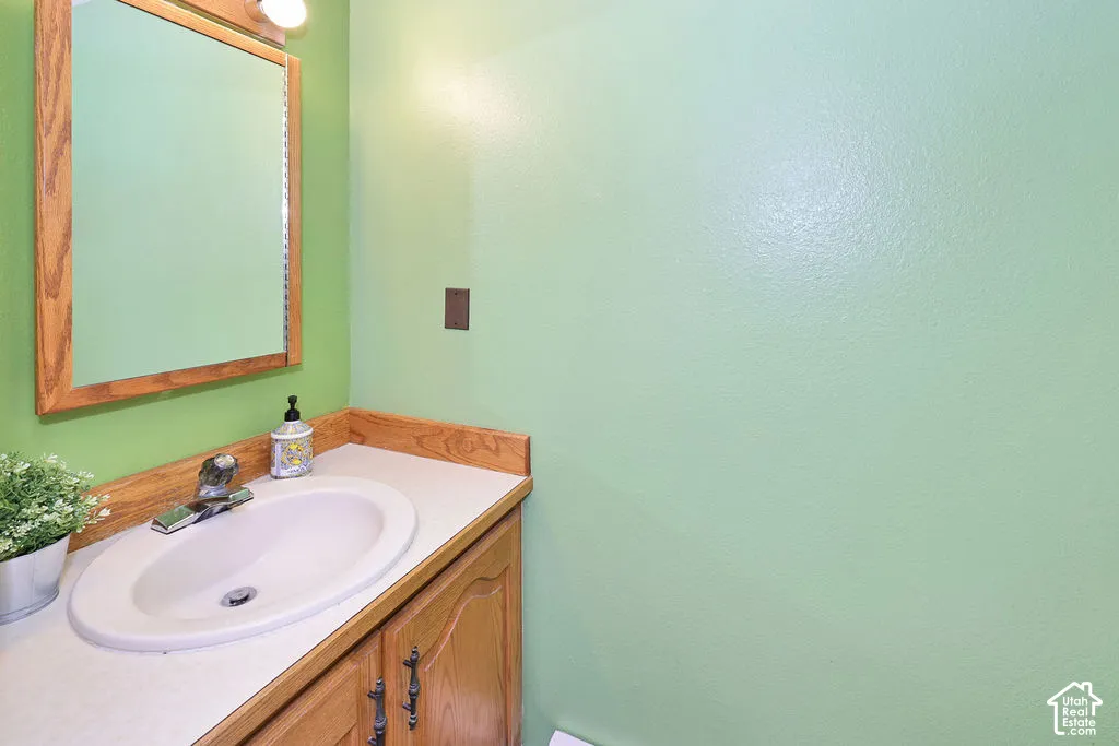 Wood-finish vanity cabinet, solid surface countertop with integrated oval sink, and wood-framed wall mirror