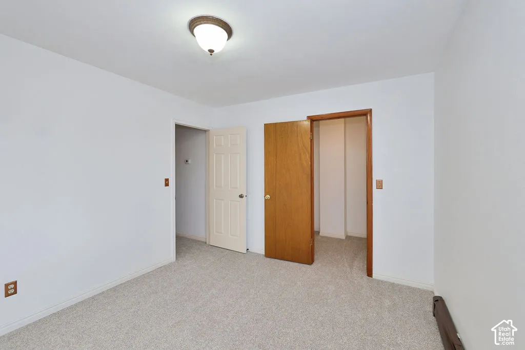 Neutral-toned wall-to-wall carpeting, six-panel interior door, and dome-style flush-mount lighting