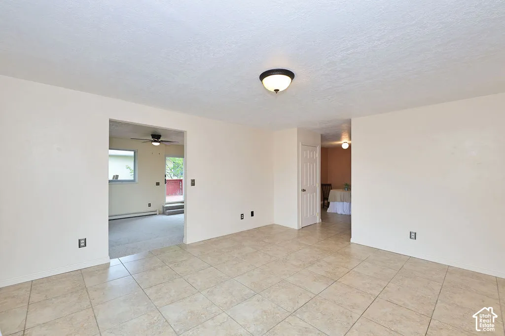 Neutral tile flooring, textured ceiling, and flush-mount lighting fixture