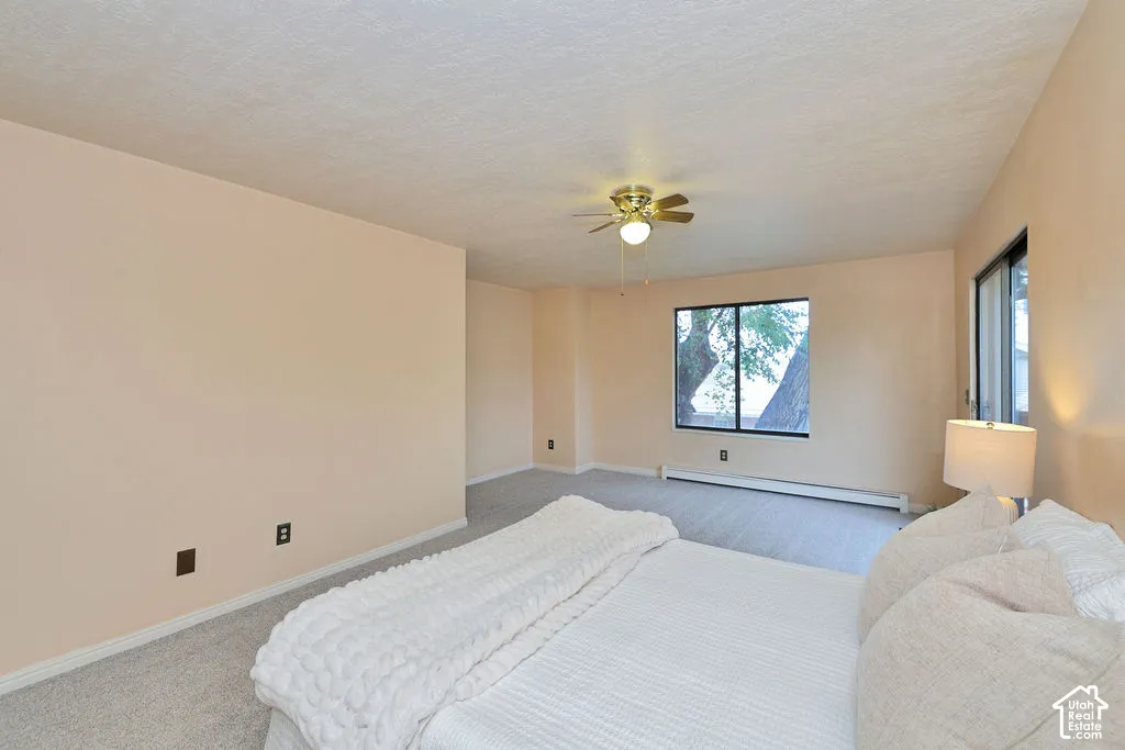 Neutral-toned interior featuring wall-to-wall carpeting, a central ceiling fan with integrated lighting, and a large window