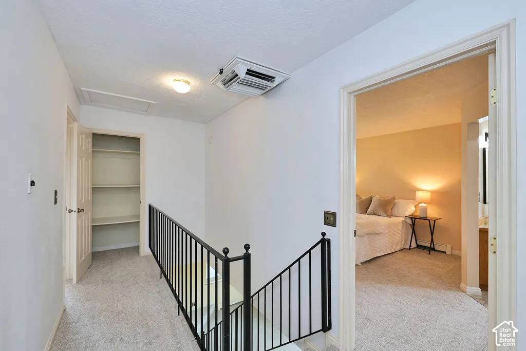 Hallway featuring carpeted flooring, built-in shelving, and black metal handrailing