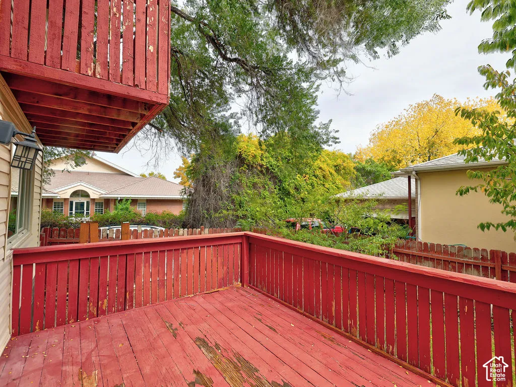 Elevated wooden deck with a red-painted finish, vertical-slat railing, and a wall-mounted exterior light fixture