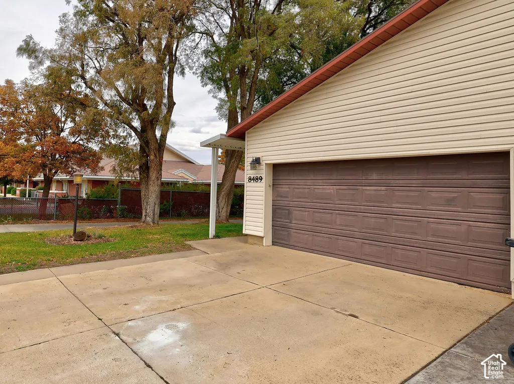 Exterior featuring horizontal siding, a multi-panel garage door, concrete driveway, and mature landscaping