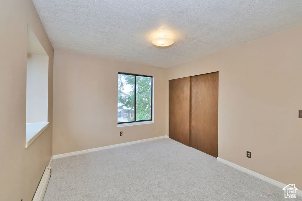 Room featuring neutral wall tones, carpeted flooring, a recessed window ledge, a sliding wood-finish closet, and a ceiling-mounted light fixture