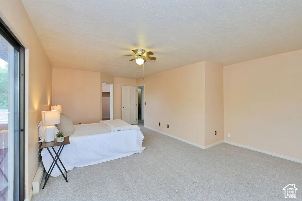 Neutral-toned room featuring neutral wall-to-wall carpeting, a central ceiling fan with integrated light fixture, and a sliding glass door