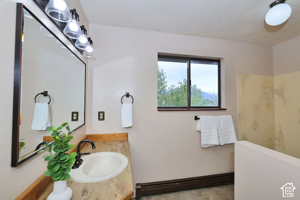 Bathroom featuring a solid-surface countertop with an integrated basin, oil-rubbed bronze fixtures, a framed wall mirror, and a window providing natural light
