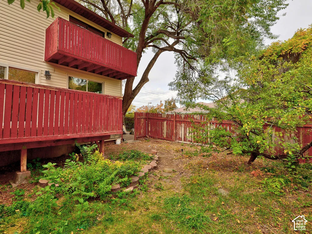 Exterior featuring a two-level wooden deck with vertical railings, cream-colored horizontal siding, stone-bordered landscaping, and enclosed yard with a wooden perimeter fence