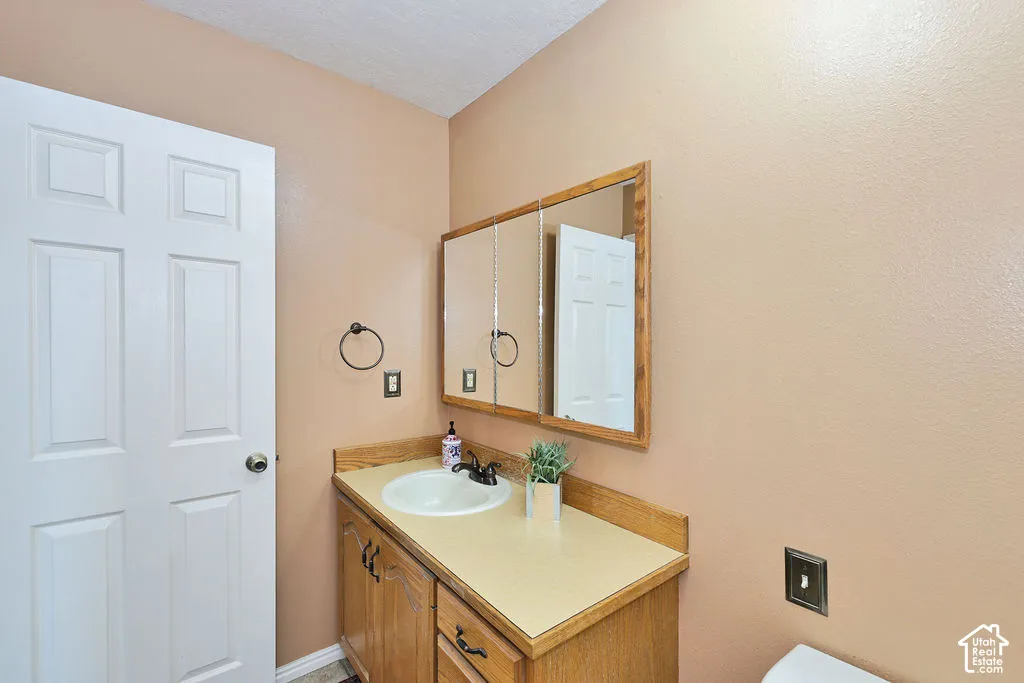 Wood-finish vanity cabinet with a solid-surface countertop, integrated basin, three-panel medicine cabinet, and oil-rubbed bronze fixtures