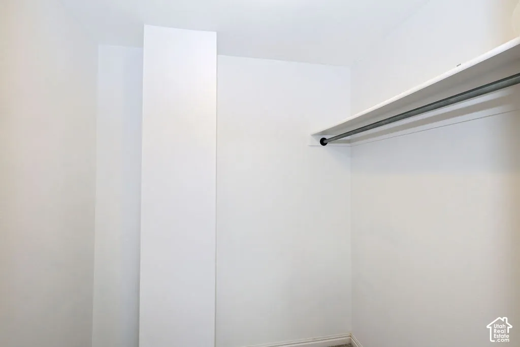 Storage area featuring a built-in horizontal shelving unit with an integrated metal garment rod