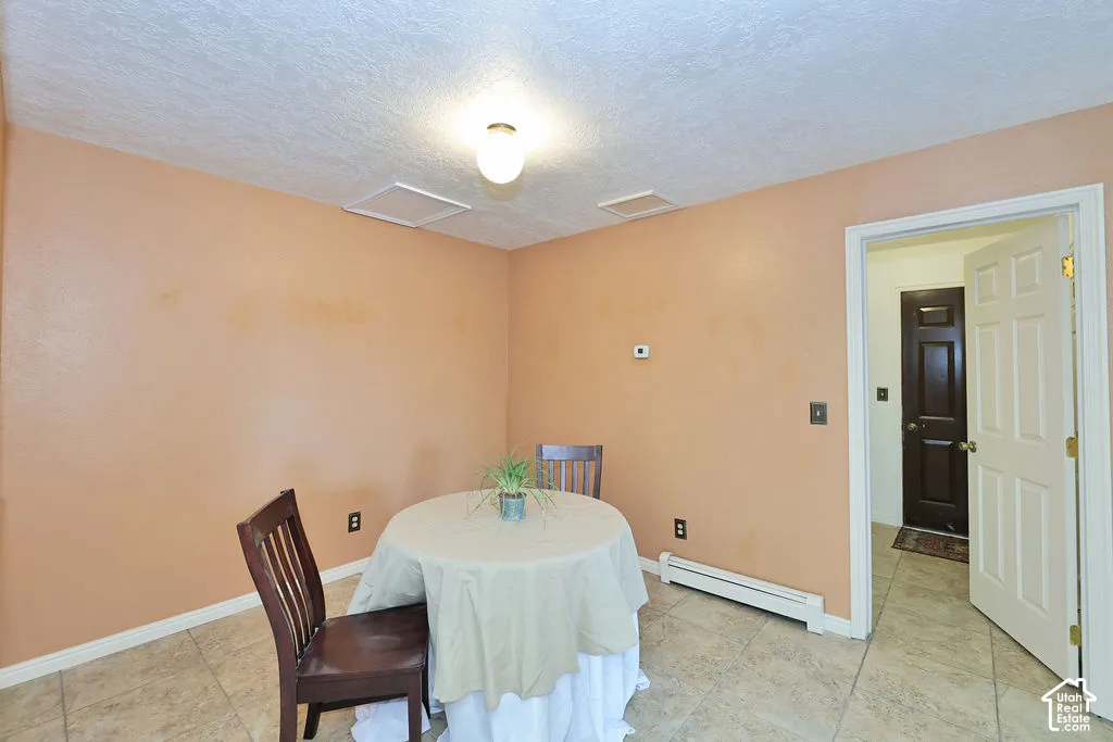 Interior space featuring textured ceiling, neutral wall finish, light-toned ceramic tile flooring, and a six-panel door