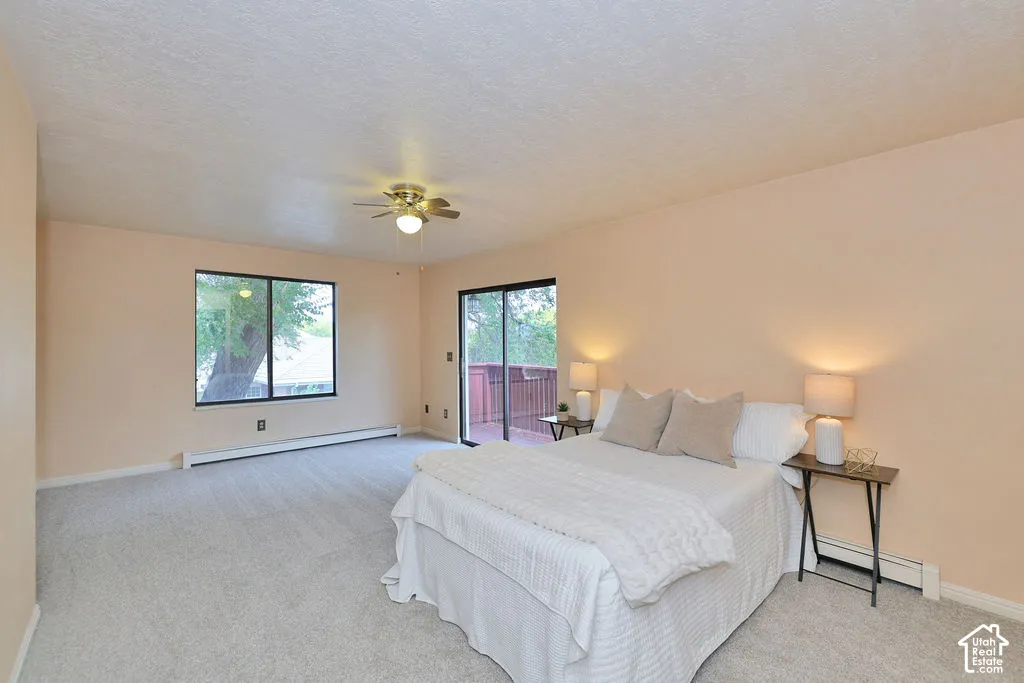 Spacious room featuring neutral carpeting, a central ceiling fan with integrated lighting, a sliding glass door, and a large window