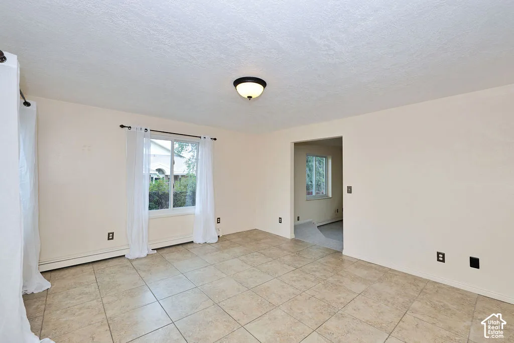 Neutral interior room featuring large-format ceramic tile flooring, a dual-pane sliding window, and a central flush-mount ceiling light fixture
