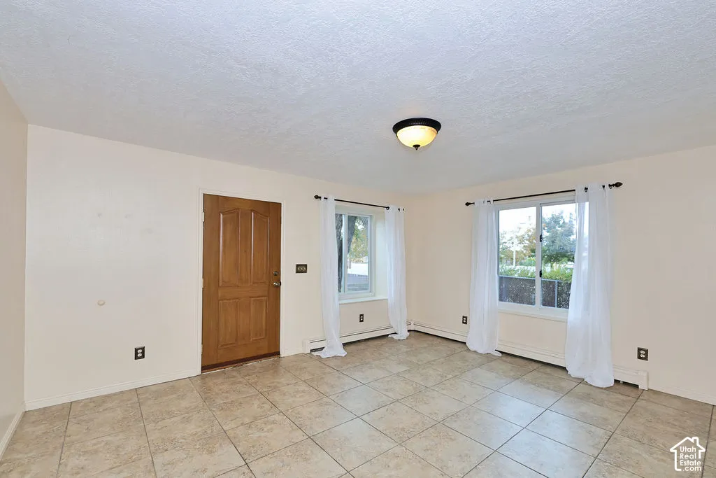 Room featuring neutral wall paint, tile flooring, a solid wood-finish entry door, and two dual-pane windows