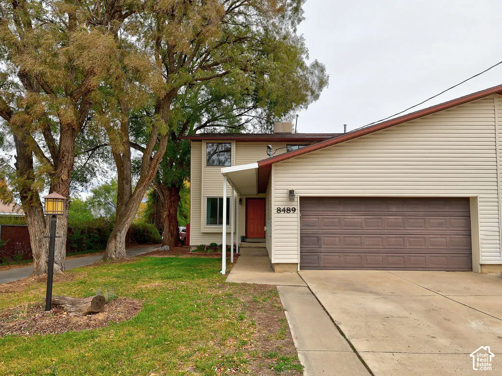 Exterior featuring horizontal siding, an attached two-car garage, a concrete driveway, and mature trees
