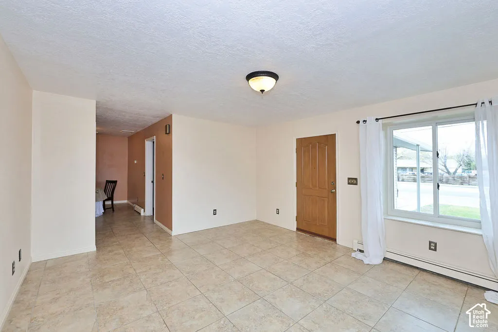 Interior space featuring large-format ceramic tile flooring, neutral wall paint, a natural wood-finish door, and a sliding window with a multi-pane configuration