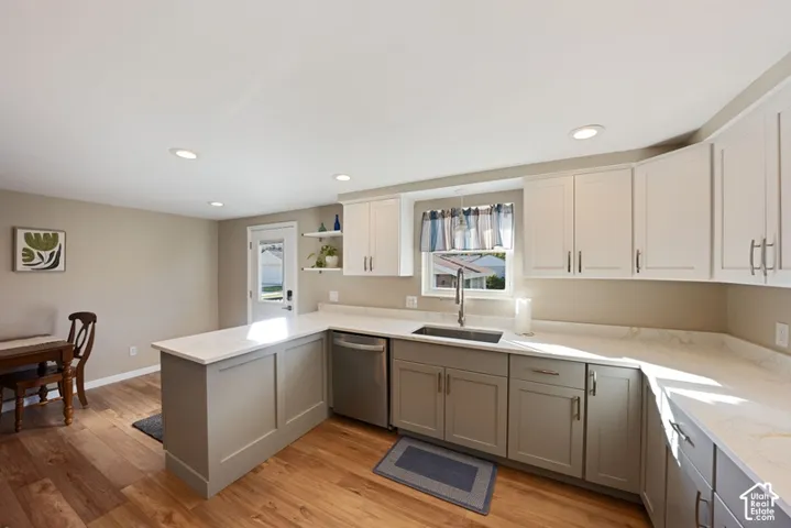 Kitchen featuring two-tone shaker-style cabinetry, light-colored countertops with subtle veining, recessed lighting, and wood-finish flooring