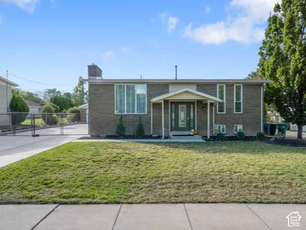 Brick exterior featuring a concrete driveway, metal privacy gate, and covered front entryway