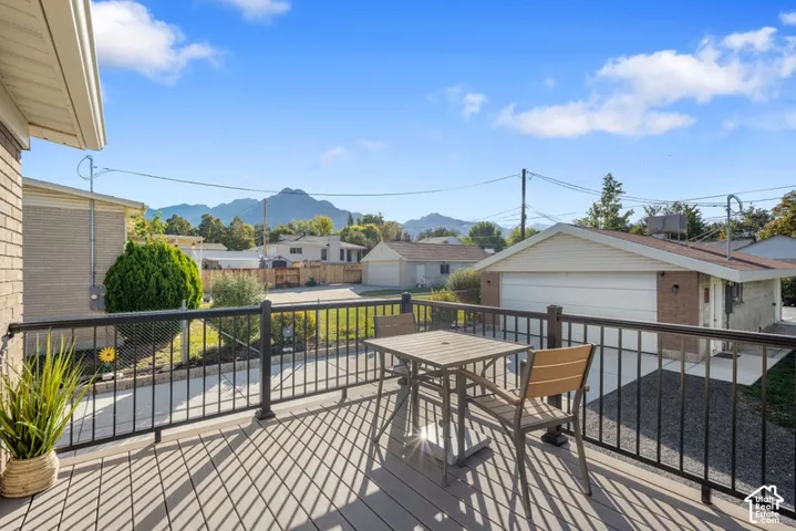 Elevated deck with metal railing, mountain scenery, and concrete driveway