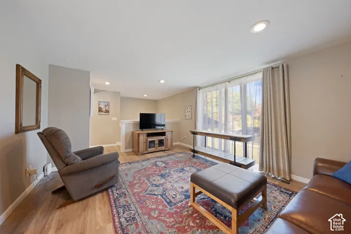 Living area featuring wood-finish flooring, recessed lighting, and expansive floor-to-ceiling glass sliding doors