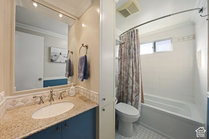 Bathroom featuring a vanity with stone-finish countertop, undermount oval sink, full-width mirror, built-in floor-to-ceiling cabinetry, and a bathtub with tile surround