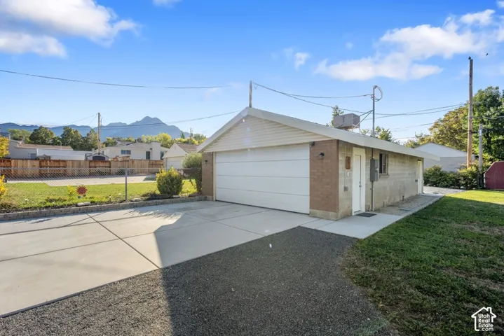 Detached garage with a white sectional door, concrete driveway, and mountain backdrop