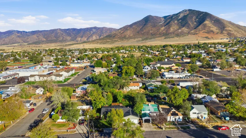 Aerial perspective featuring established residential streets with mature trees and a prominent mountain range backdrop