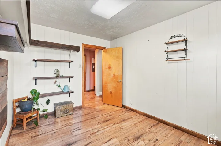 Vertical paneled walls, wood-finish flooring, and built-in wooden shelving units