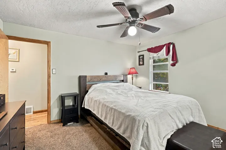 Room featuring textured ceiling, neutral wall paint, overhead ceiling fan with light fixture, and single-pane window