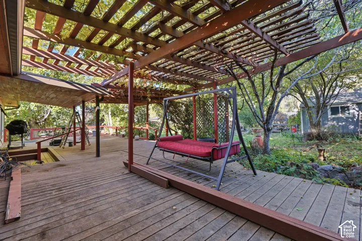 Expansive wood deck featuring an overhead slatted pergola, integrated wood railings, and lattice privacy screening