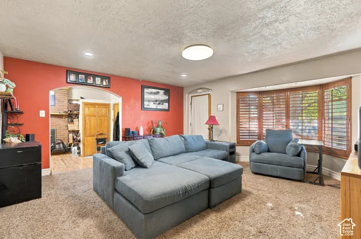 Living area featuring an arched entryway, bay window with wood shutters, and recessed lighting