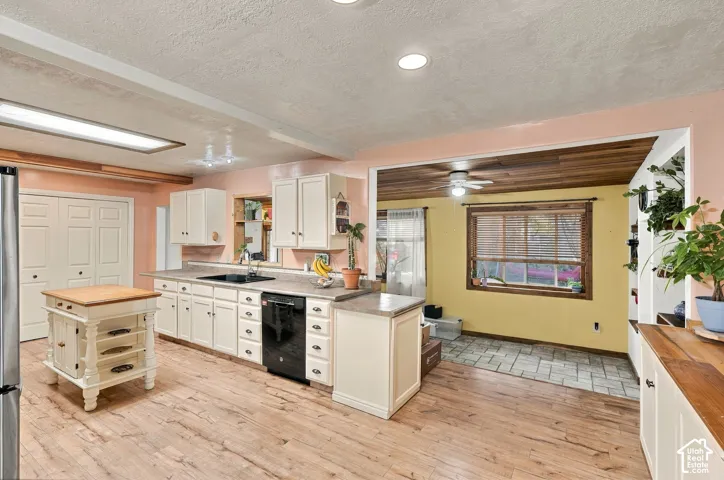 Kitchen featuring wood-finish flooring, white cabinetry, a built-in kitchen island, a window with wood trim, and a tile-floored area with a wood-plank ceiling