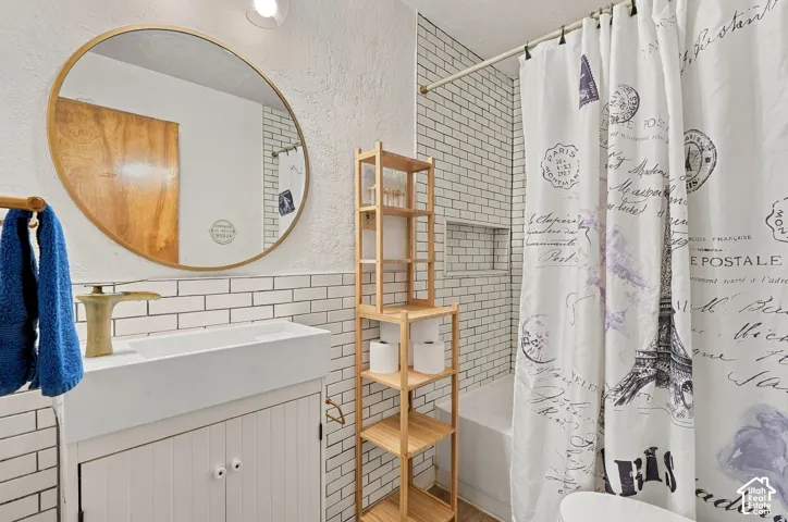 Bathroom vanity with an integrated rectangular sink and metallic faucet, round mirror with a thin frame, white subway tile walls, and a built-in recessed wall niche