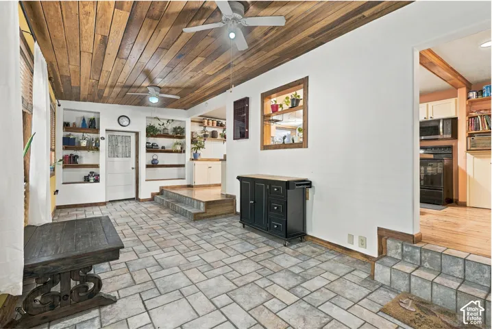 Wood-plank ceiling featuring dual ceiling fans, tile flooring, and integrated wall shelving