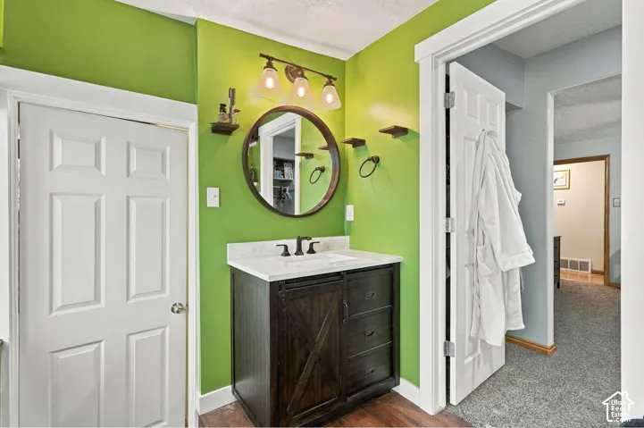 Bathroom vanity featuring a dark wood-finish cabinet, stone-composite countertop with an integrated rectangular basin, matte black faucet, and a circular wall-mounted mirror