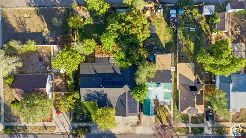 Aerial perspective of the property featuring a shingled roof, roof-mounted solar panel arrays, and mature landscaping