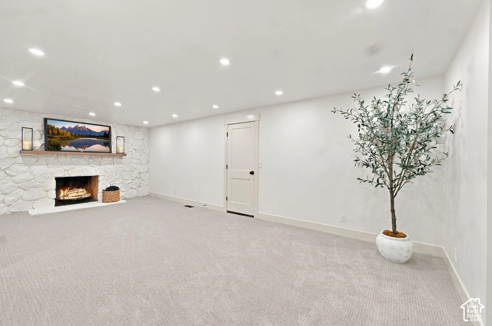 Finished basement featuring recessed ceiling lighting, neutral carpet flooring, and a fireplace with decorative surround