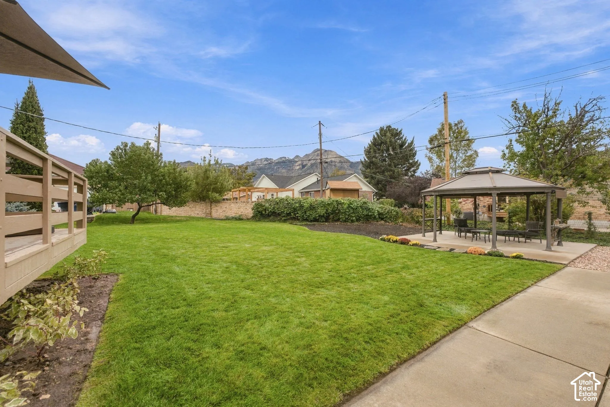 Expansive backyard featuring a manicured lawn, mature landscaping, and multiple hardscaped patios