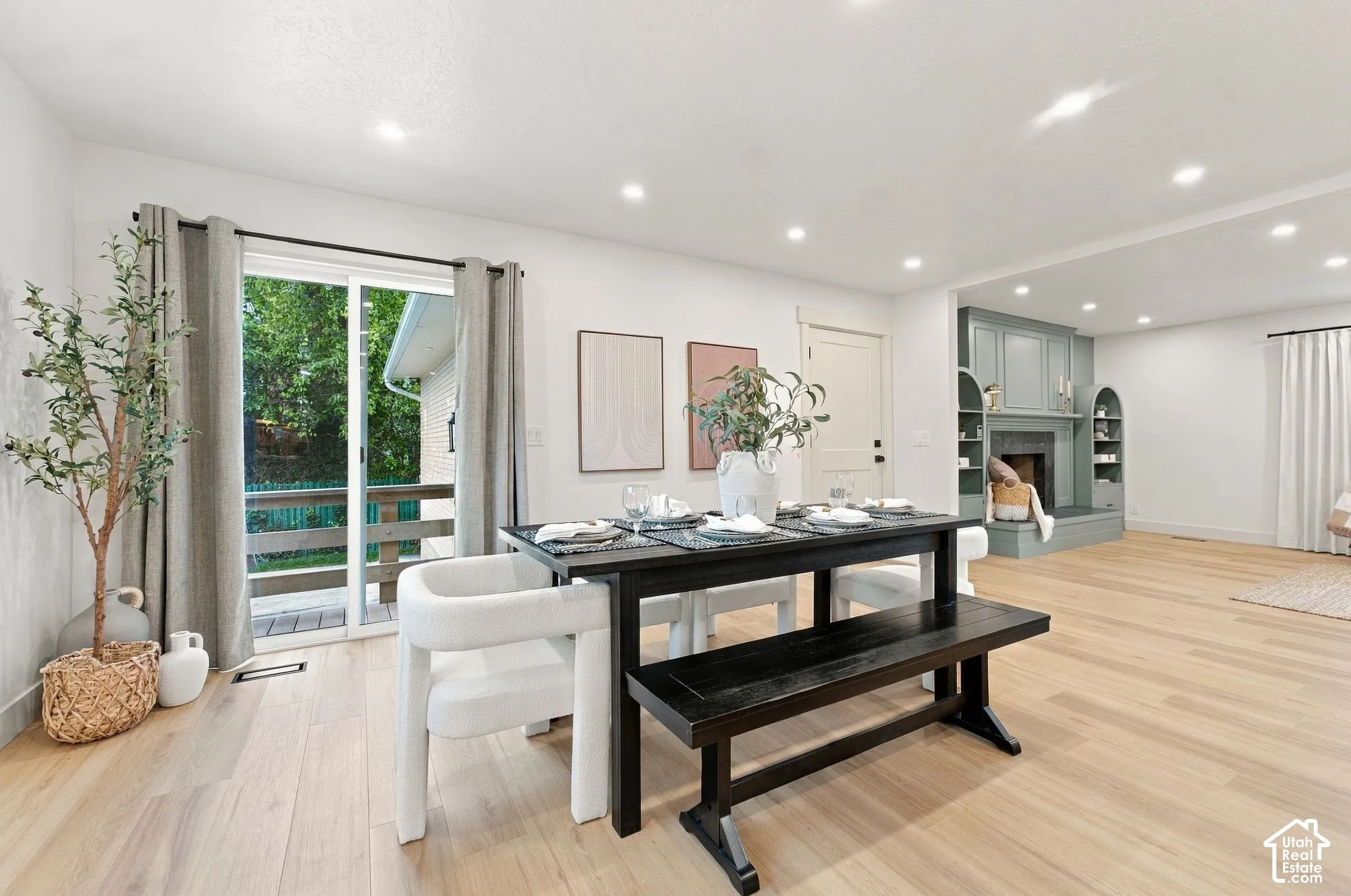 Open-concept space featuring wood-finish flooring, recessed lighting, a sliding glass door with exterior access, and a fireplace framed by built-in cabinetry with arched detailing
