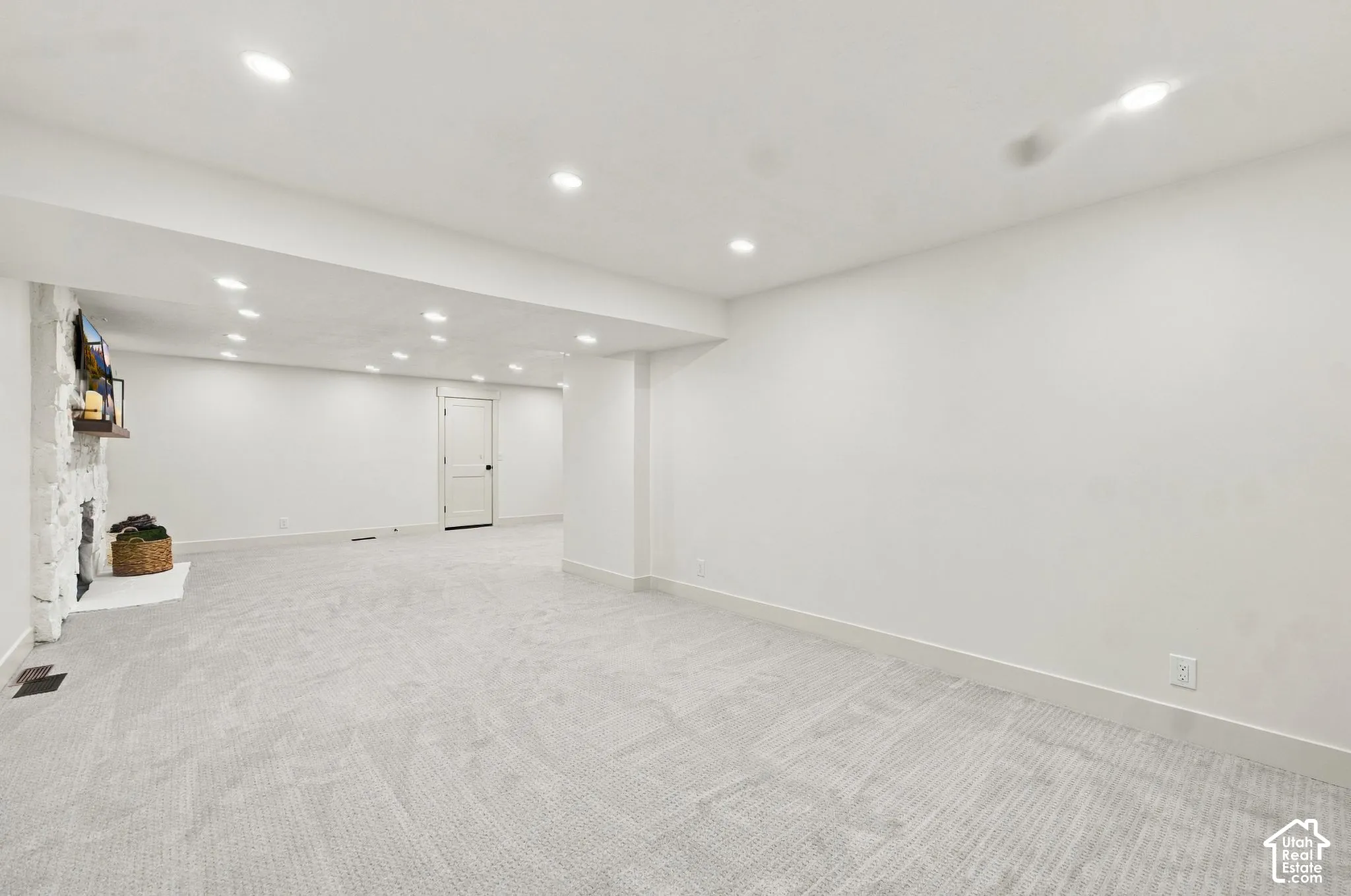 Open-concept interior space featuring recessed ceiling lighting, wall-to-wall carpeting, and a stone-clad fireplace surround
